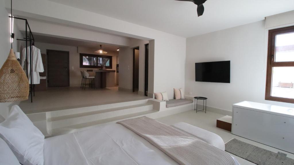 a white living room with a couch and a television at Ianos Living Spaces - 02 in Korinthos