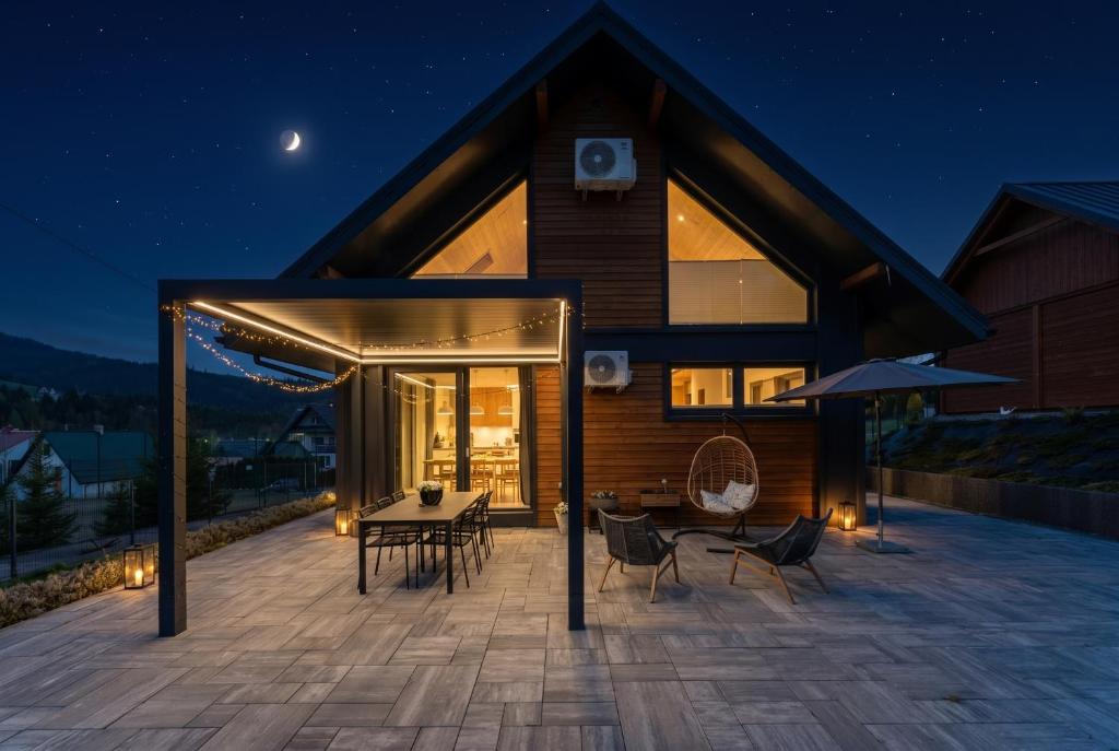 a house with a deck at night with a table and chairs at Stasiówka in Sablówka