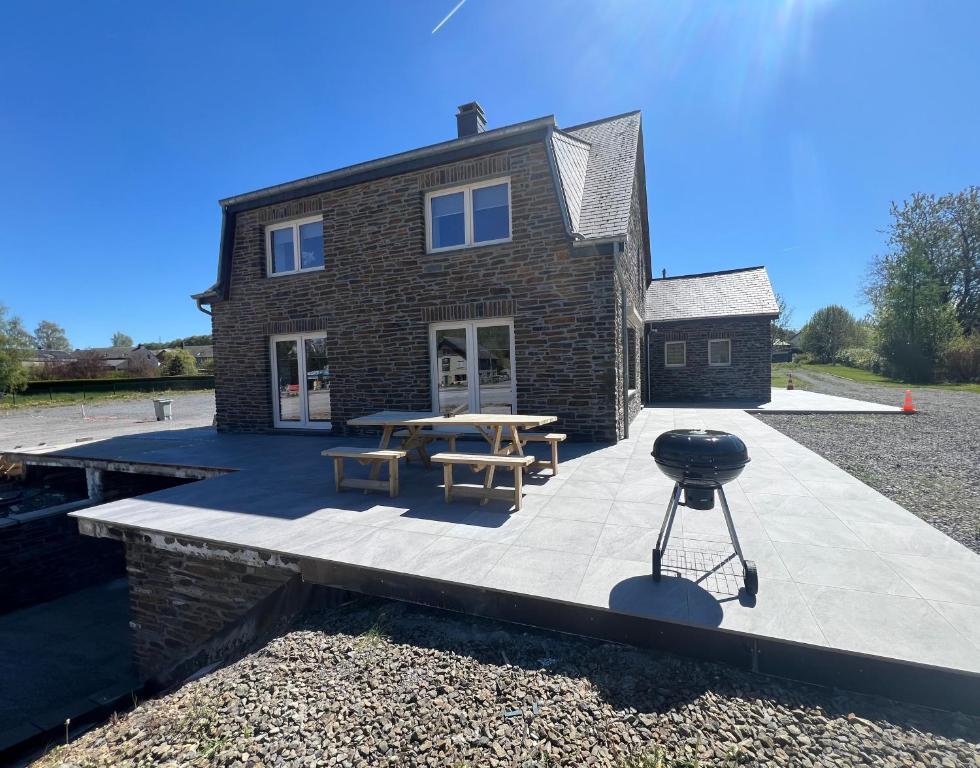 a patio with a table and a grill in front of a house at Le repaire de la n4 in Tenneville