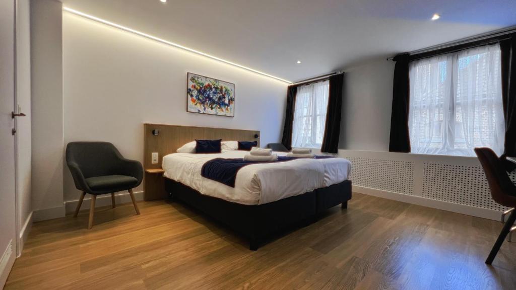 a bedroom with a bed and a chair in it at Hotel Montovani in Bruges