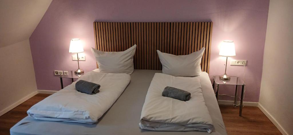 a bedroom with two beds with pillows and two lamps at Hotel Birnbaum in Ansbach