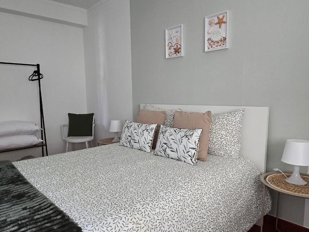 a white bedroom with a bed and a chair at JB House in Peniche