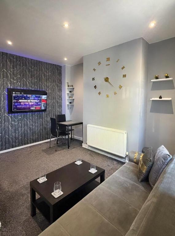 a living room with a couch and a clock on the wall at Central 2 Bed House in Huddersfield