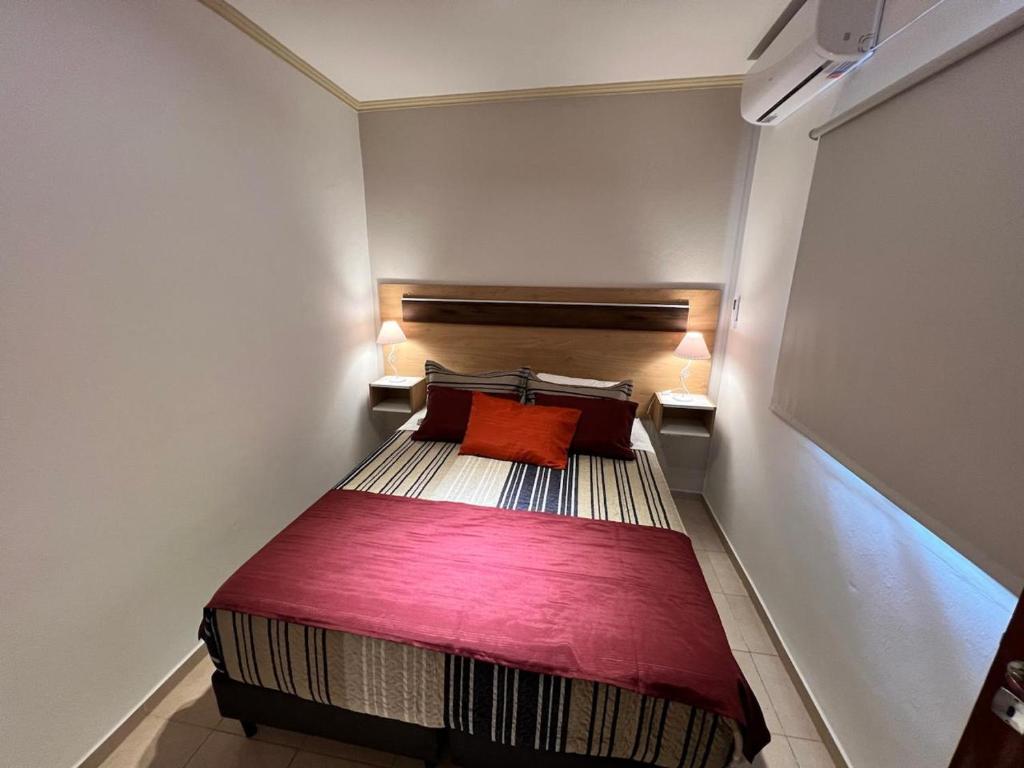 a small bedroom with a bed with a red pillow at Alojamiento Guemes II in San Fernando del Valle de Catamarca