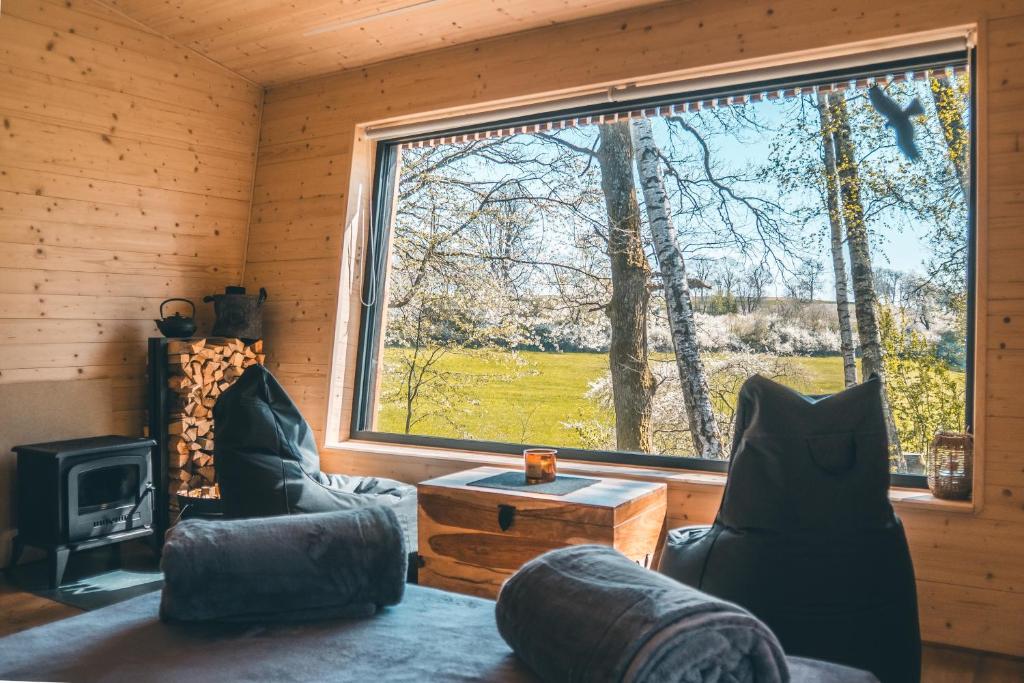 a living room with a large window in a log cabin at Rokle Tiny house Plandry in Plandry