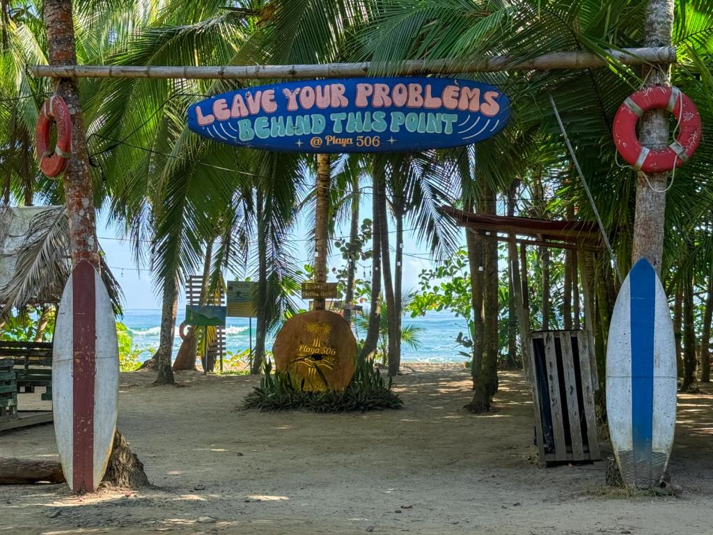 ein Schild an einem Strand mit Surfbrettern am Strand in der Unterkunft Playa 506 Beachfront Hostel in Puerto Viejo