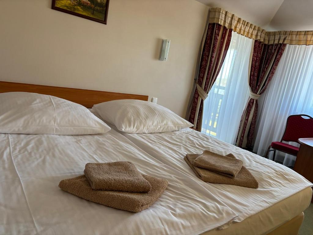 a bed with two towels sitting on top of it at Hotelik Zełwągi in Mikołajki