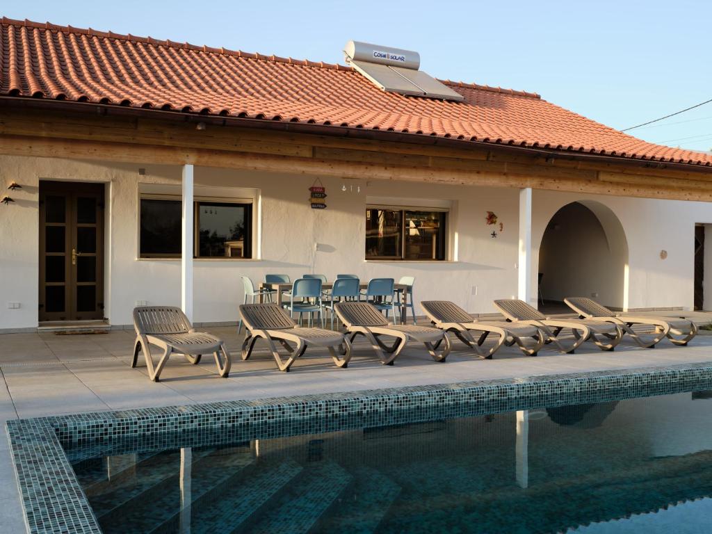 a pool with chairs and tables and a house at Casa Da Liberdade in Alte