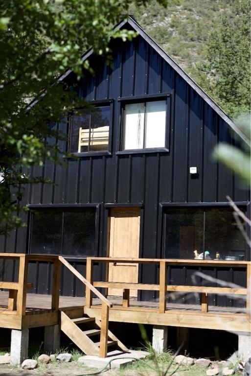 a black house with a wooden staircase and windows at Rayen Mahuida - Las Trancas in Las Trancas