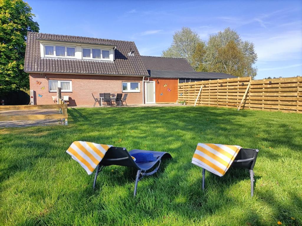 two chairs in the grass in front of a house at Bargerveenhuis in Weiteveen