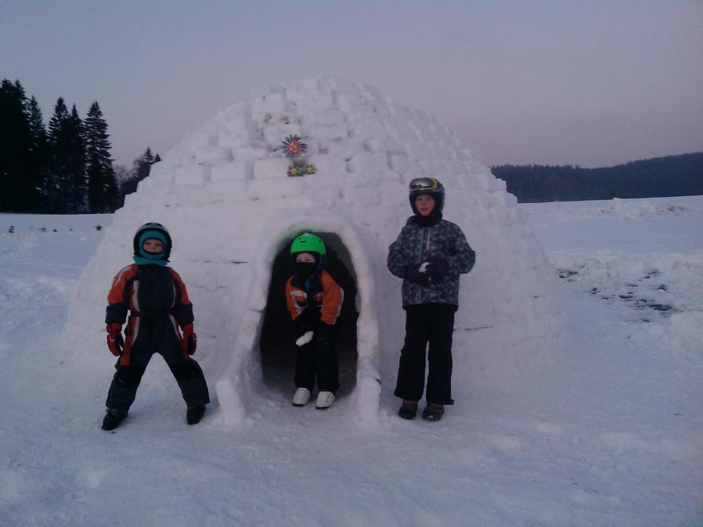three children standing in front of a snow igloo at Apartmány Kuřátko in Benecko