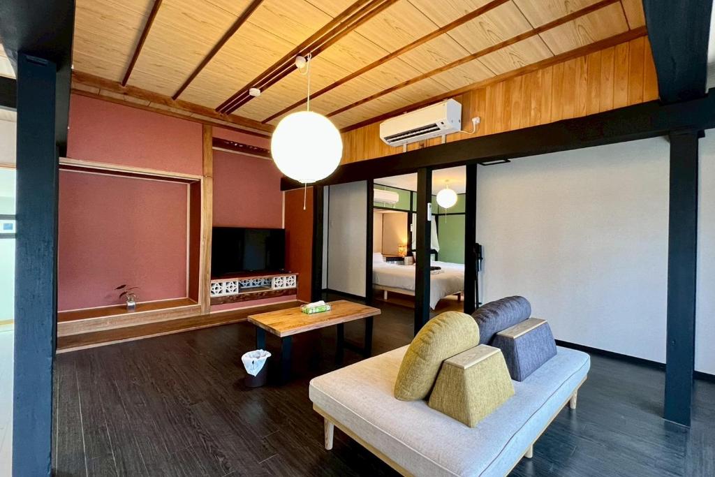 a living room with a couch and a bedroom at あざみ庵 奄美大島 in Amami