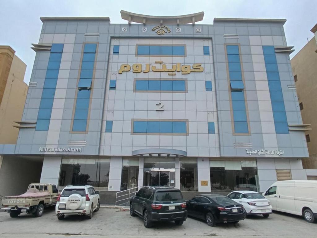 a large building with cars parked in a parking lot at Quiet Rooms 2 Serviced Apartments in Riyadh