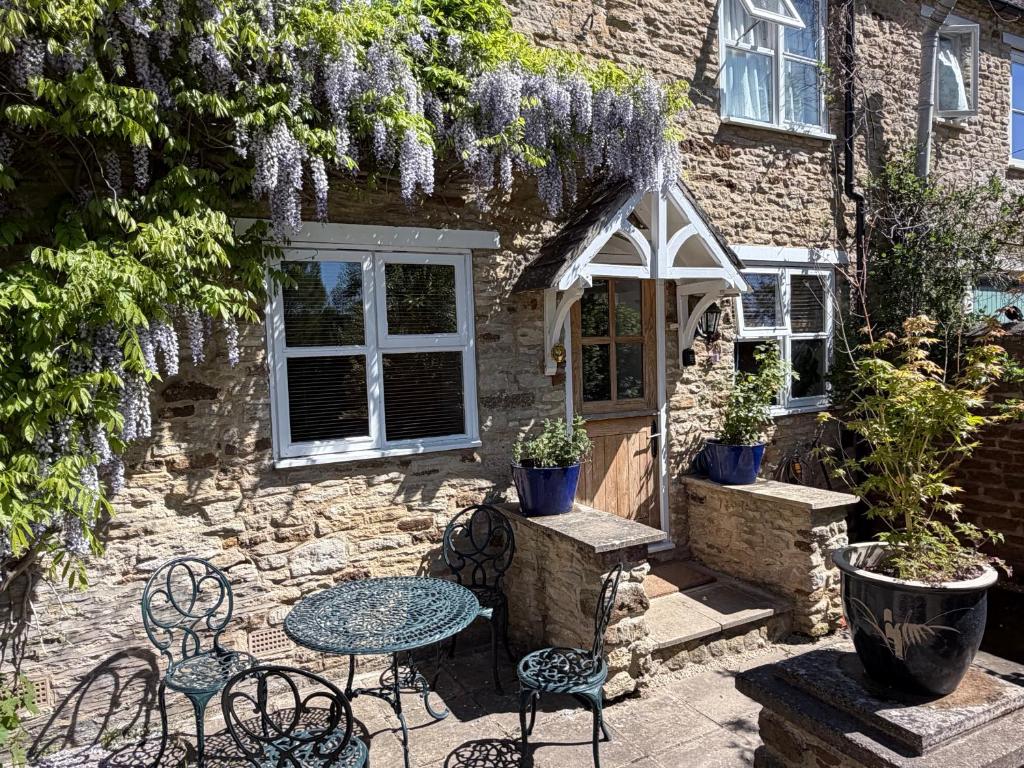 a table and chairs in front of a stone building at Cotswold Cottage in Steeple Aston