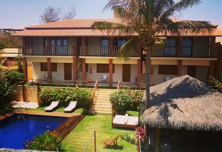 a house with a palm tree and a swimming pool at Pousada Dona Flor in Canoa Quebrada