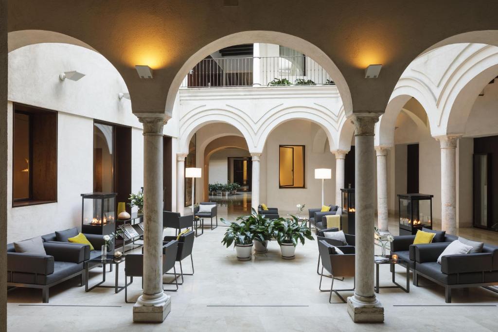 a lobby with chairs and tables in a building at Hotel Posada del Lucero in Seville