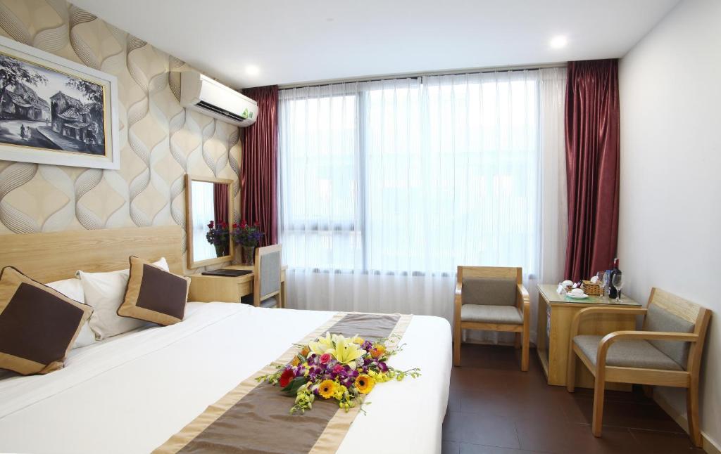 een hotelkamer met een groot bed met bloemen erop bij Blue Pearl Hanoi Hotel in Hanoi
