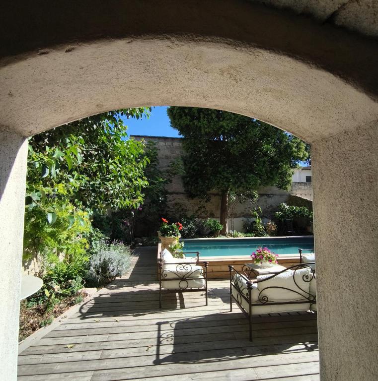an archway with two chairs and a swimming pool at VILLA ADOYA Chambre d'hôtes Aigues-Mortes intra muros au calme climatisation réversible PISCINE WIFI ascenseur PARKING gratuit in Aigues-Mortes
