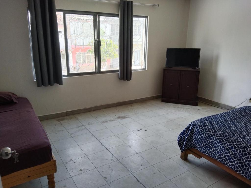 ein Schlafzimmer mit einem Bett und einem Fernseher in der Unterkunft Hostal Batarse Centro in Torreón