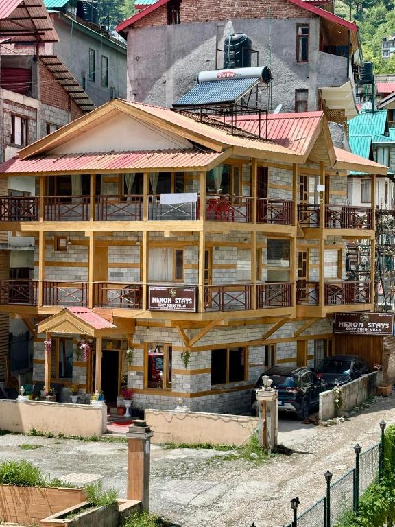 a wooden building with a balcony on a street at Hexon Stays in Manāli