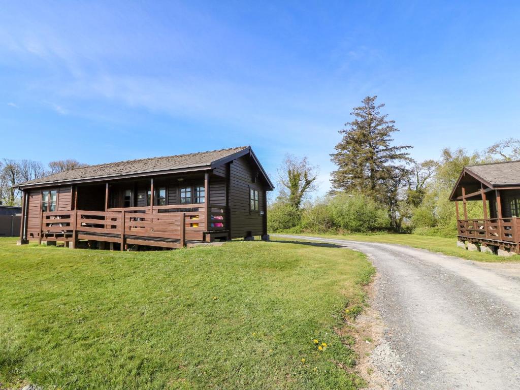 a house on a grassy hill next to a road at Lodge 1 - Bron Eifion in Criccieth