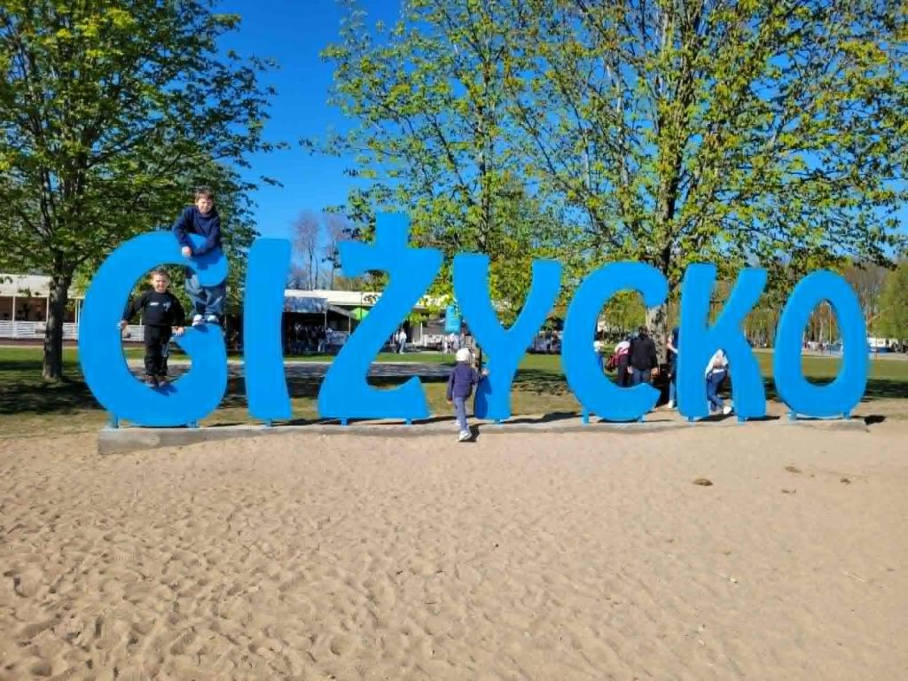 a group of people standing in front of a large sign at Lake Hill Giżycko in Giżycko