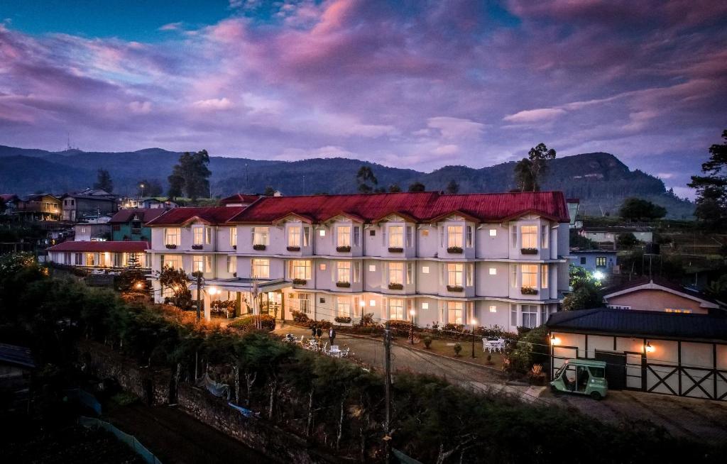 a large white building with a red roof at night at Galway Heights Hotel in Nuwara Eliya