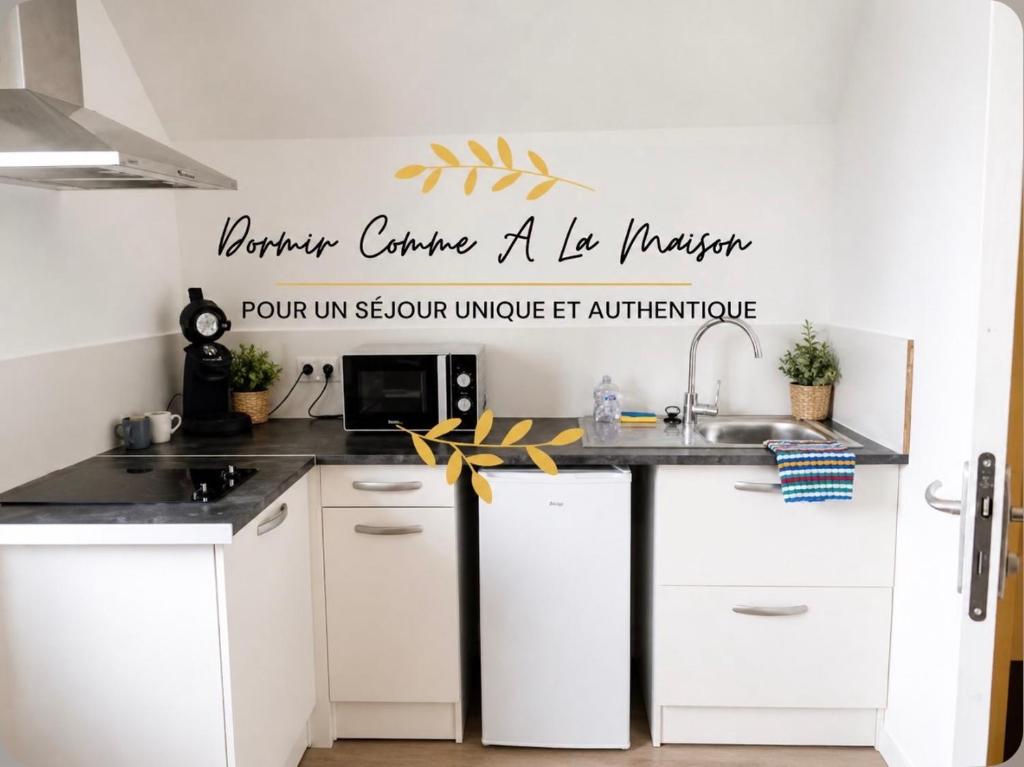 a kitchen with white cabinets and a sink at Bienvenue à Saint Julien De Vouvantes - Dormir Comme A La Maison in Saint-Julien-de-Vouvantes