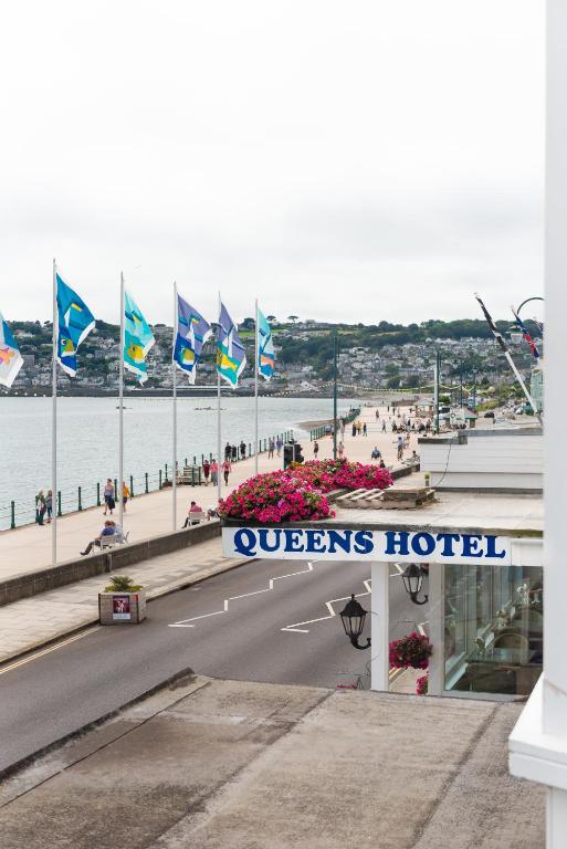 a sign for a queens hotel with flags on a bridge at The Queens Hotel in Penzance