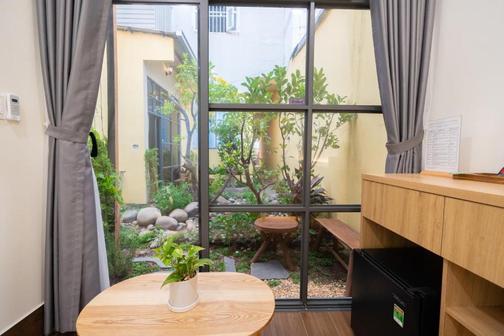 a room with a window with a table and a garden at Cái Vườn Ấm in Lái Thiêu
