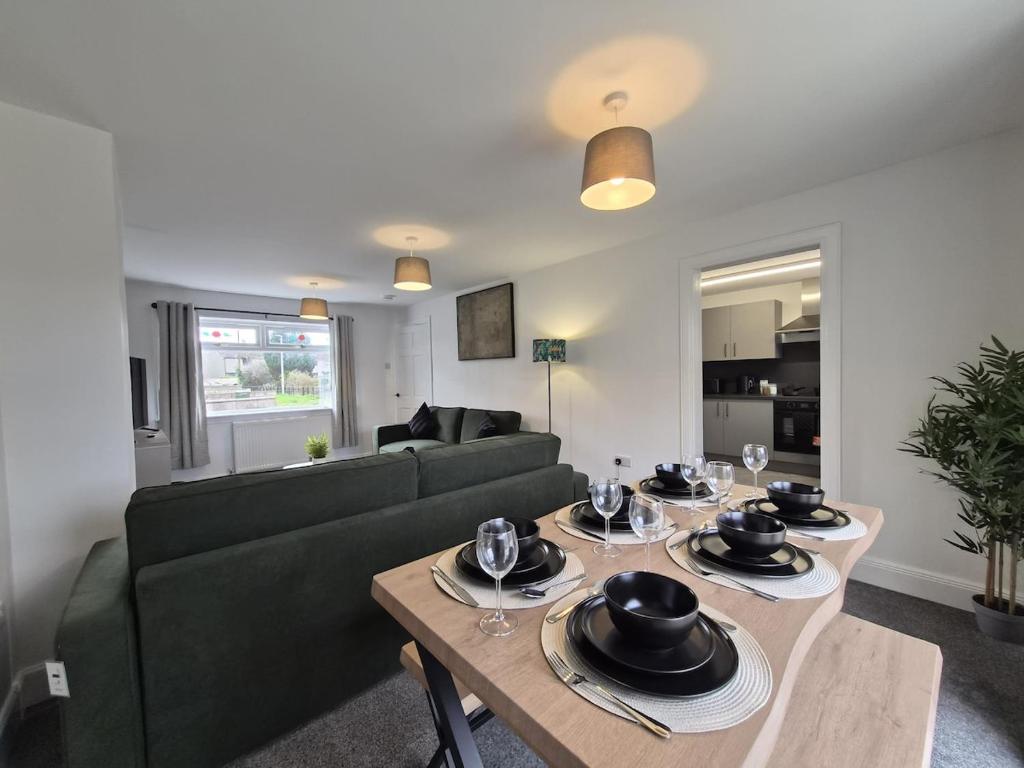 a living room with a green couch and a table at Spacious 3 Bedroom House with Large Drive in Dundee