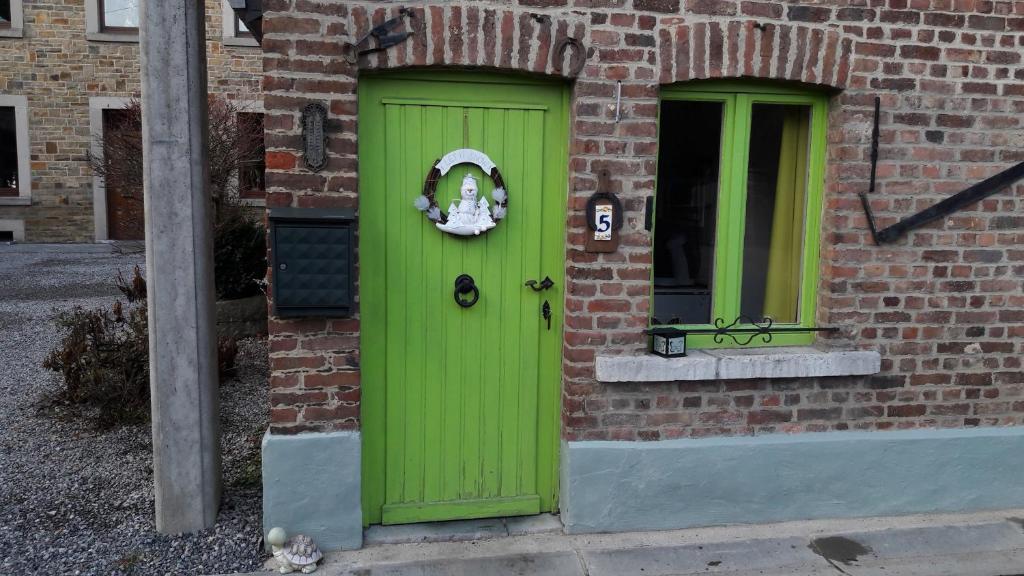 una porta verde sul lato di un edificio in mattoni di Le Petit Papillon a Durbuy