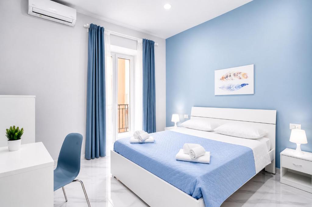 a blue and white bedroom with a bed and a chair at Neve Al Sole Modern Suites near Metro Materdei in Naples Center in Naples