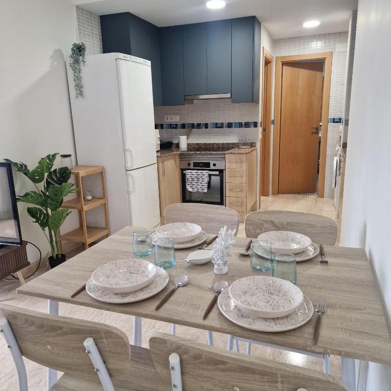 a wooden table with plates and glasses on it in a kitchen at Apartamento Mar Blava Chilches in Chilches
