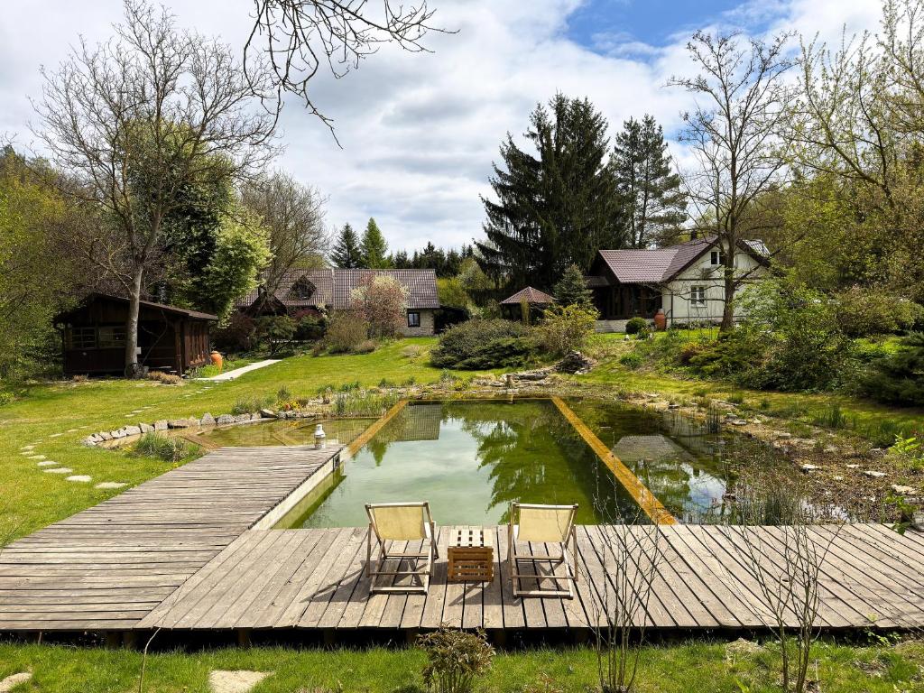 a wooden dock with two chairs and a pond at Pokoje gościnne Fermata in Kazimierz Dolny