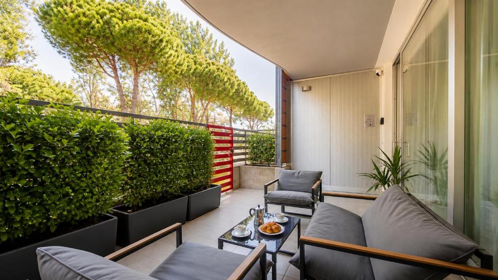 an apartment patio with couches and a hedge at Appartamento Residence Mimose - con parcheggio e Terrazza vicino al mare in Eraclea Mare