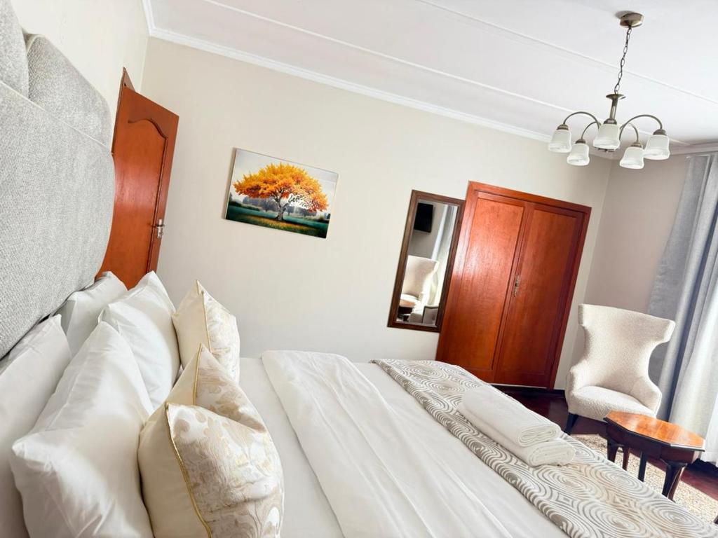 a white bedroom with a bed and a chair at Rugira Guest House in Vosburg