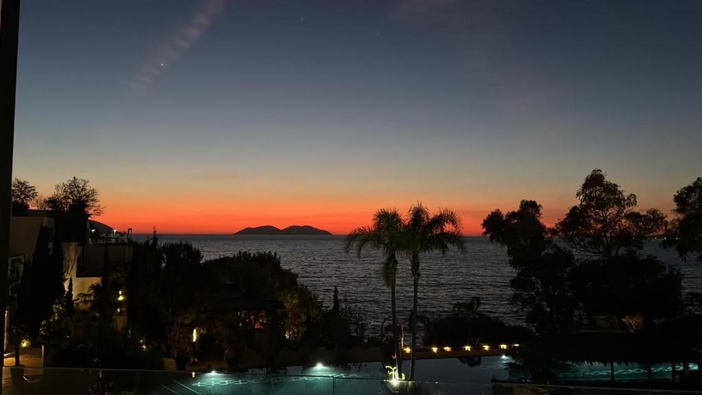 a sunset over a body of water with palm trees at Marina Bay Apartament 1 in Vlorë