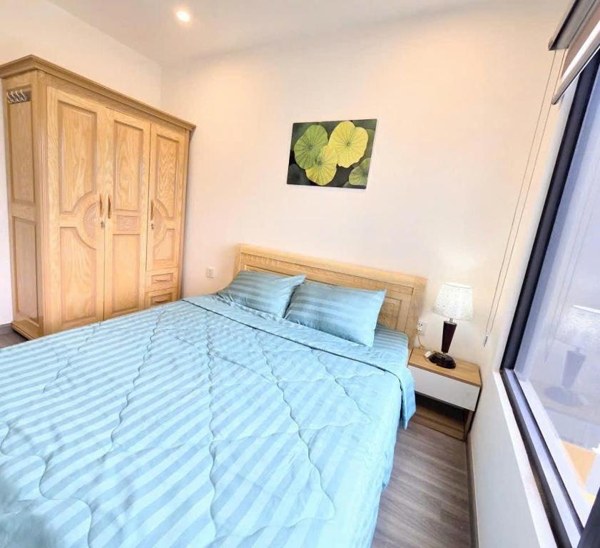 a bedroom with a bed with a blue comforter at TUỆ Home in Long Bình