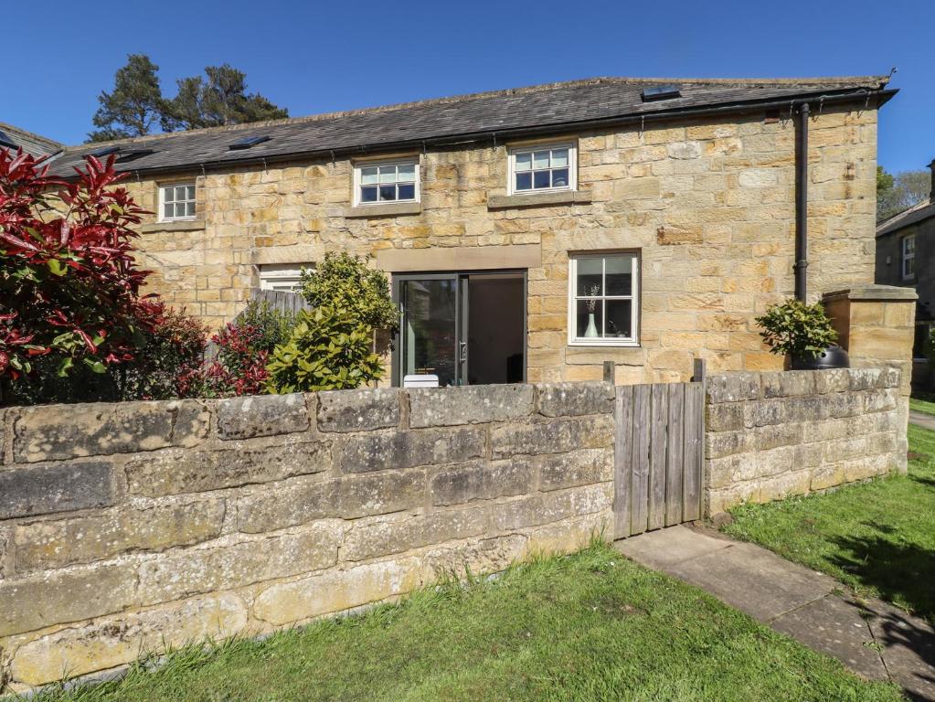 a stone house with a retaining wall at Snowdrop Cottage in Morpeth