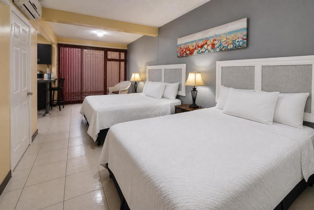 a hotel room with two beds and a desk at Hotel Bamboo Aeropuerto in Alajuela
