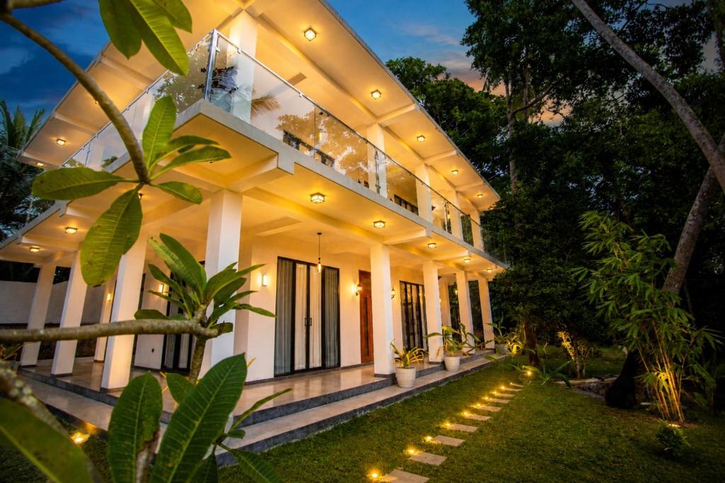 a white house with lights in front of it at Villa 9 March in Unawatuna