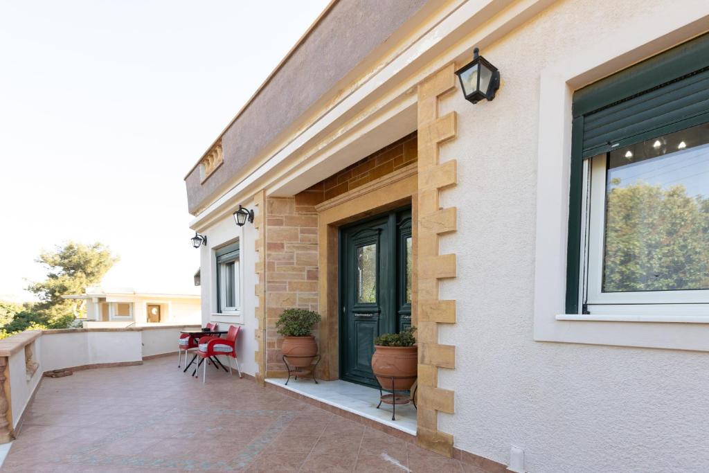 a building with a porch with chairs and a window at Aeolus Villa Chios in Chios