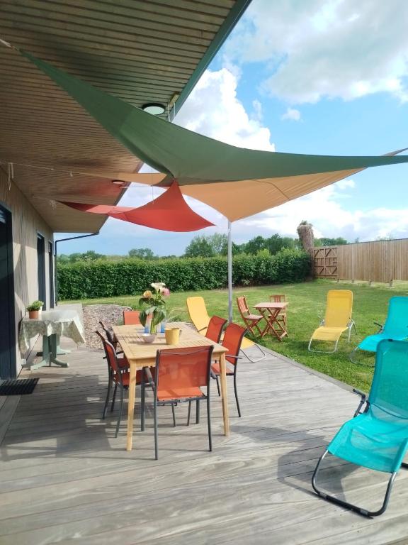 a patio with a table and chairs under a umbrella at Gîte des Peupliers in Courlay