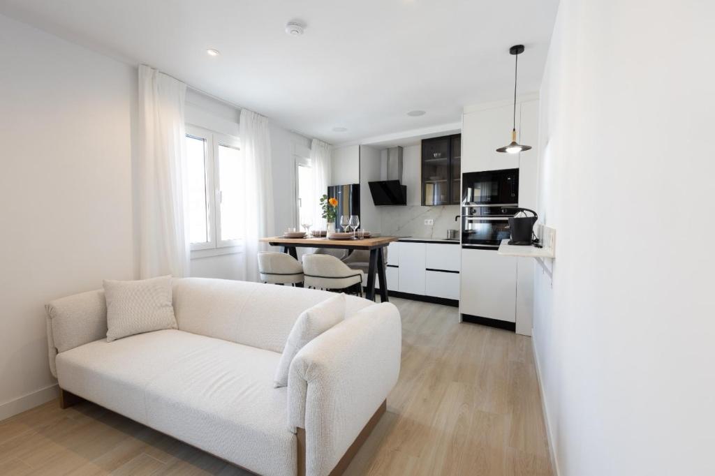 a white living room with a white couch and a kitchen at Apartamentos La Búsqueda in Cuenca