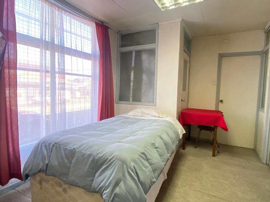 a bedroom with a large bed and a red table at Hostal Cochrane in Valdivia
