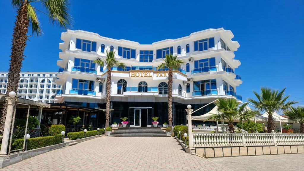 biały budynek z palmami przed nim w obiekcie Fari Hotel w mieście Golem