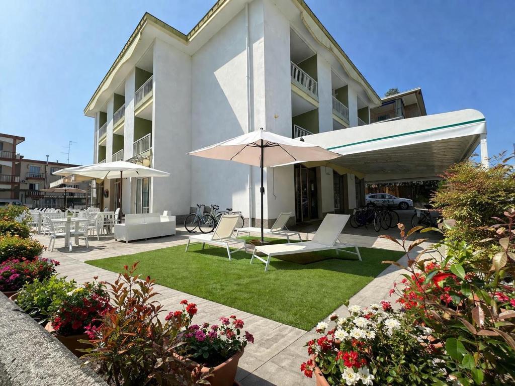 a building with a patio with chairs and an umbrella at Hotel ai Fiori in Grado