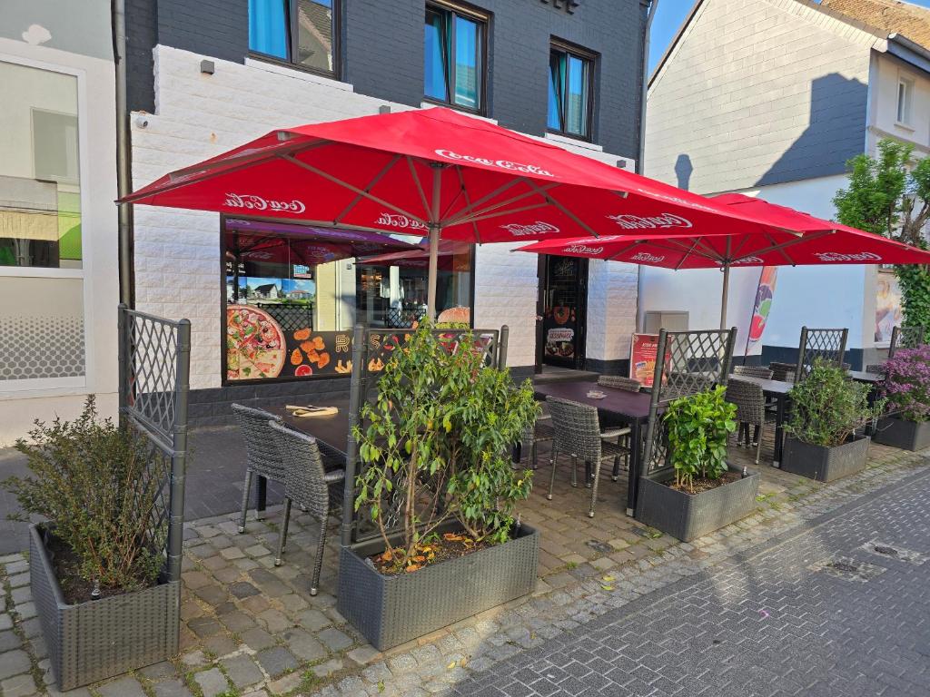 a restaurant with tables and chairs with red umbrellas at RS Zimmervermietung in Zülpich