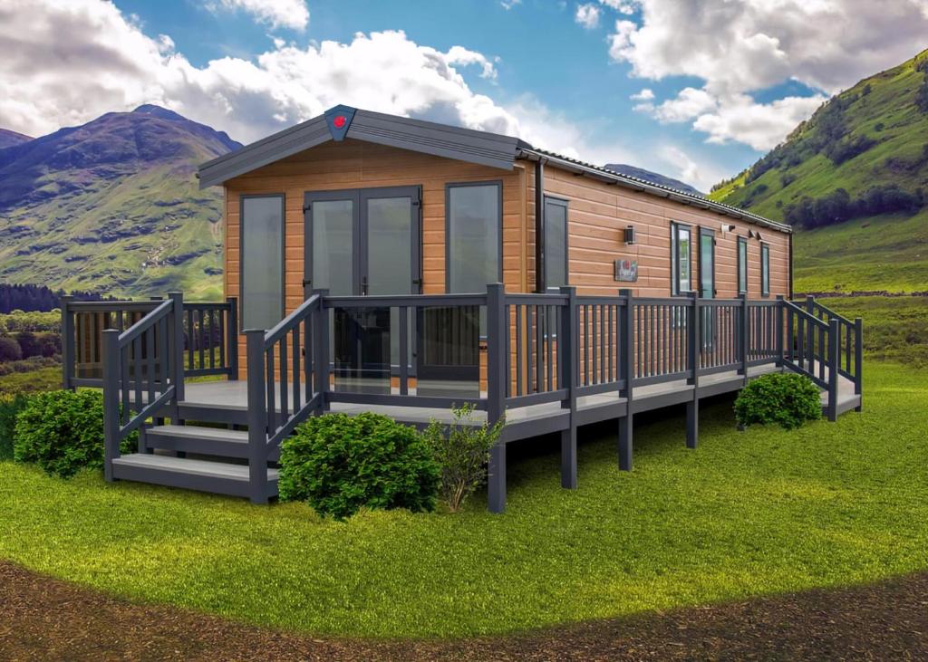 a wooden cabin with a large deck in the grass at Benview Lodges in Kemnay